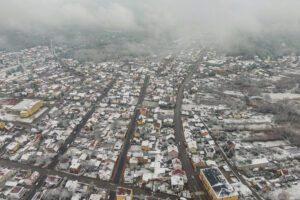 Zdjecie miasta wykonane z drona. Miasto przecinają trzy ulice. Domy przyprószone śniegiem