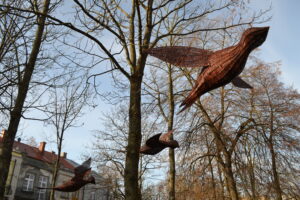 Trzy ptaki wykonane z wikliny zawieszone między drzewami